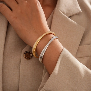 Close-up of 18k gold and silver plated cross bangles with shimmering pavé zircon stones