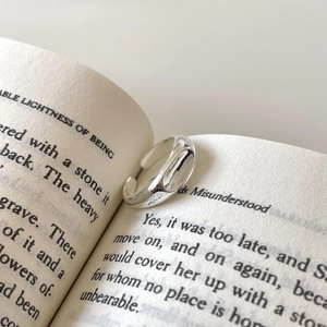 Minimalist 925 sterling silver open ring with irregular concave design on an open book