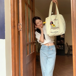 Detail of off-white canvas tote bag featuring dog embroidery and drawstring closure