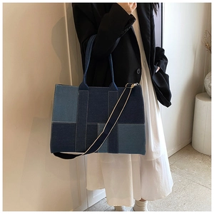 Close-up of patchwork denim tote bag with blue geometric panels and wide shoulder strap