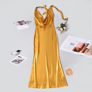 Dettaglio dell'abito lungo in raso dorato con scollo a cappuccio e accessori eleganti