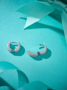 Close-up of silver hoop earrings with full pavé diamonds on a blue gift box