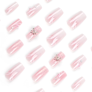 Pink gradient press-on nails with silver bows, pearls, and glitter on white background