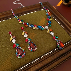 Detail of vintage jewelry set with red pear-cut stones on green velvet display