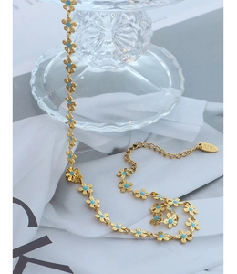 Macro view of K18 gold flower chain with sky blue petals on white fabric
