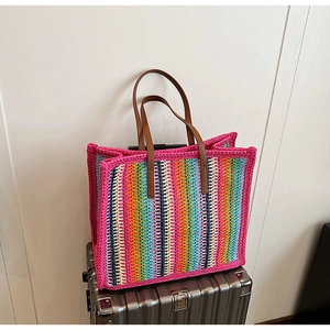 Detail of colorful striped crochet tote bag with brown leather handles on luggage
