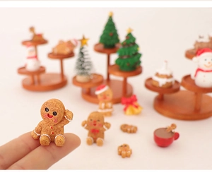 Miniature Christmas gingerbread man and snowman figurines displayed on a wooden shelf