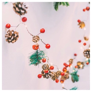 Macro detail of Christmas LED string lights with red berries, pine cones and needles