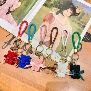 Detail view of six colorful resin teddy bear keychains with knitted textures and ribbons