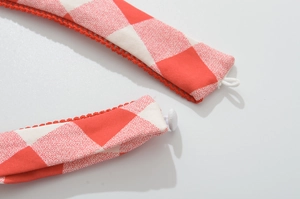 Detail of red and white plaid halter dress fabric with red lace trim and button closure