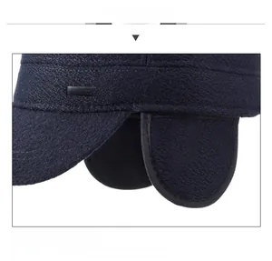 Detailed view of the dark blue winter hat's thick fabric, earflaps and metal fashion logo