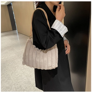 Dettaglio borsa in peluche beige con strisce verticali e anelli metallici sulla tracolla