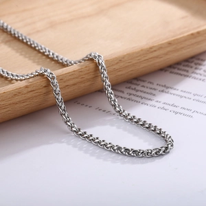 Dettaglio della collana a catena in acciaio inossidabile argento su vassoio in legno
