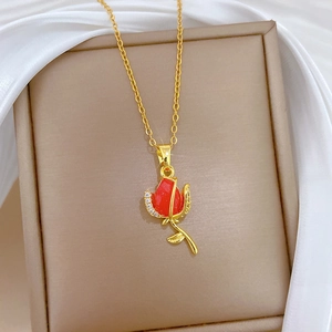 Detailed macro of a red tulip pendant with crystals on a golden necklace over silk