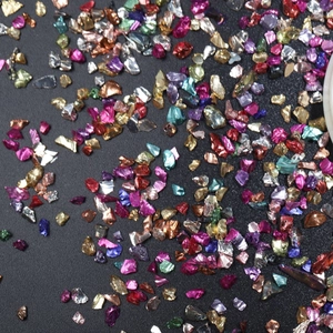 Macro shot of colorful irregular glass shards for nail art DIY on a dark background