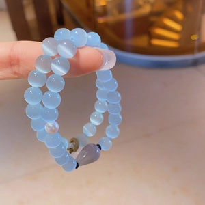 Close-up of light blue cat eye stone beads with a pearl and droplet pendant