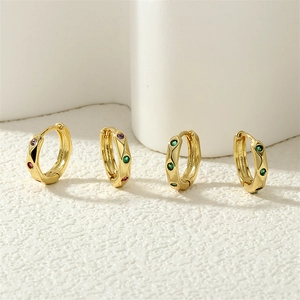 Detailed macro view of small gold hoop earrings set with colorful zircon gemstones