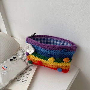 Detailed shot of rainbow striped crochet bag with white cloud patch and colorful pom-poms
