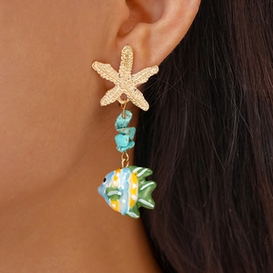 Detail of starfish stud and colorful tropical fish drop earring worn on ear