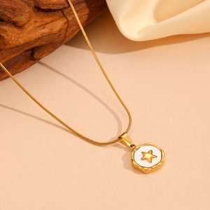 Macro view of gold snake chain with white enamel pendant and golden star detail