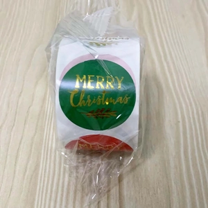 Macro shot of gold foil Merry Christmas sticker roll with festive holiday designs