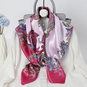 Elegant 90cm paisley print satin scarf in pink and gold on a white shirt and handbag