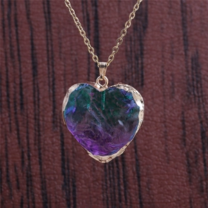 Detail of gold heart pendant with iridescent purple and green raw resin stone on gold chain