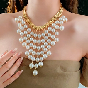 Dettaglio della collana a catena dorata con frange di perle a strati su una modella