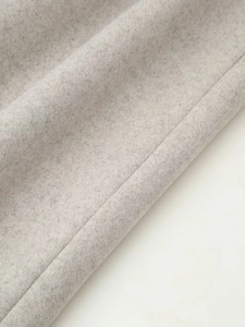 Macro shot of gray wool blend fabric showing fine texture and detailed stitching on the coat