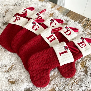 Detailed view of red knitted Christmas stockings with white embroidered alphabet letters