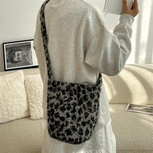 Detail of grey leopard print plush shoulder bag with wide strap on a model