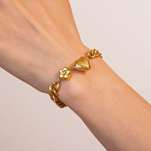 Detail of gold chain bracelet with heart and star pendants on a model's wrist