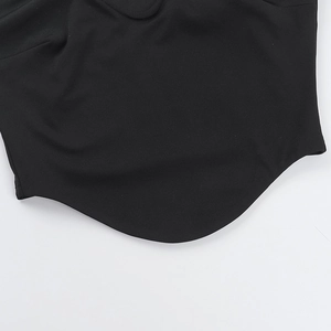 Détail du design de l'ourlet incurvé d'un haut noir amincissant à épaules dénudées