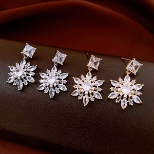 Macro shot of gold and silver snowflake earrings with cubic zirconia on leather
