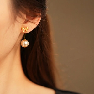 French vintage gold bow earrings with lustrous pearls on a model in close-up view