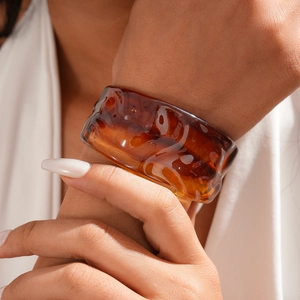 Detailed view of amber resin cuff bracelet with wavy texture on model wrist