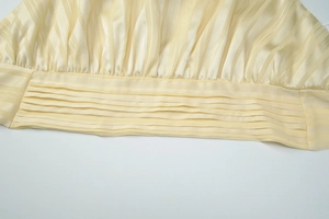 Detail of cream backless top showing vertical stripe texture and waist pleat design