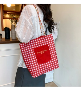 Detalle del bolso tote de cuadros rojos y blancos con bolsillo y correas tejidas