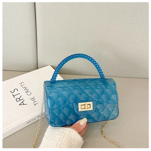Close-up of blue jelly bag featuring quilted pattern, gold chain and beaded handle