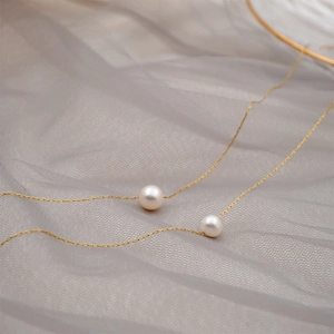 French retro gold chain necklace with two white pearls on a soft grey tulle background