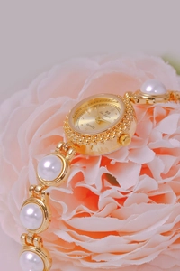 Macro shot of gold pearl bracelet watch with quartz movement on a pink flower
