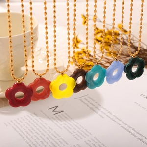Gold chain necklaces with colorful resin flower pendants in a lifestyle setting