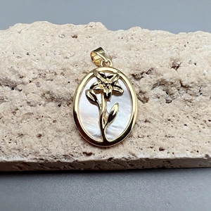 Detail of oval white shell flower pendant with gold metal frame on stone base