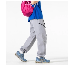 Detail view of light grey cargo pants with adjustable elastic cuffs and side zipper pocket