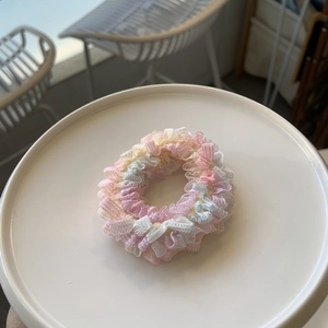 Détail d'un chouchou en dentelle multicolore aux textures de maille rose et bleu pastel