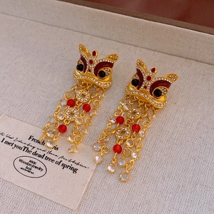 Gros plan de boucles d'oreilles lion chinois avec perles rouges et détails de pièces