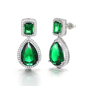 Close-up of teardrop emerald earrings with halo diamond setting and silver plating