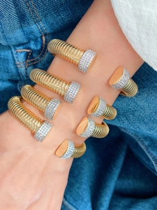 Macro shot of gold Tubogas bracelets with pave-set rhinestones on denim background