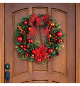 Close-up of Christmas wreath with red bow and pine cones on a dark wooden door