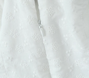 Detailed close-up of white floral embroidery and invisible zipper on the sexy halter dress